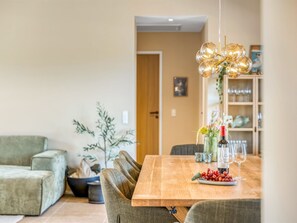 Ein Essbereich mit Holztisch, Stühlen, einer Blumenvase und einer Weinflasche.