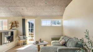 A modern living room with a sofa, a coffee table, and a TV mounted on the wall. - "Indra" - 800m from the sea by Interhome (Løkken)