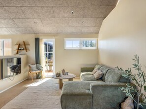 A modern living room with a sofa, a coffee table, and a TV mounted on the wall. - "Indra" - 800m from the sea by Interhome (Løkken)