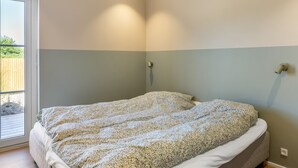A bedroom with a bed, a window, and a wall-mounted light fixture. - "Indra" - 800m from the sea by Interhome (Løkken)