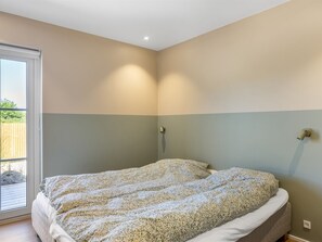 A bedroom with a bed, a window, and a wall-mounted light fixture. - "Indra" - 800m from the sea by Interhome (Løkken)