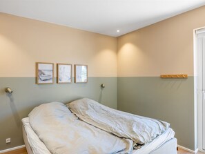 A bedroom with a bed, a wall-mounted light, and three framed pictures. - "Indra" - 800m from the sea by Interhome (Løkken)