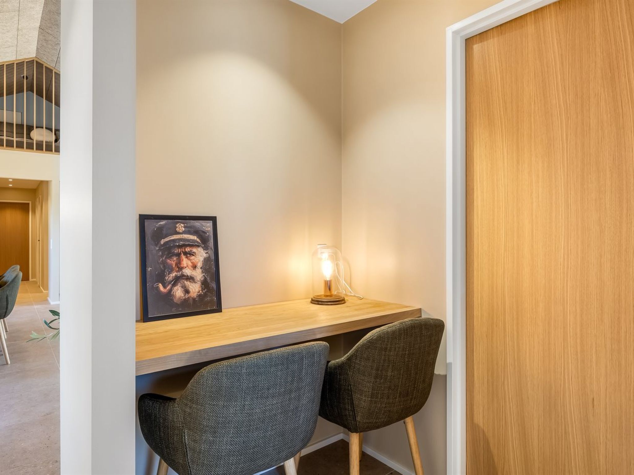 A small workspace with a desk, two chairs, a framed picture, and a lamp.