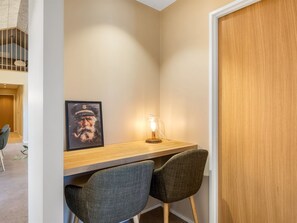 Un petit espace de travail comprenant un bureau, deux chaises, un tableau encadré et une lampe.