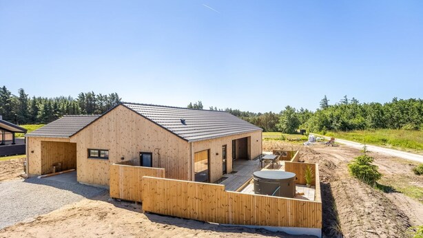 A wooden cabin with a large deck area and a hot tub. - "Indra" - 800m from the sea by Interhome (Løkken)