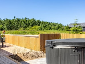 A wooden deck with a hot tub, a wooden fence, and a person in the background. - "Indra" - 800m from the sea by Interhome (Løkken)