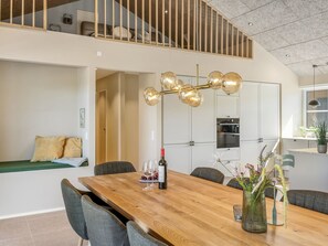 A modern dining area with a wooden table, chairs, a wine bottle, and a decorative vase. - "Indra" - 800m from the sea by Interhome (Løkken)