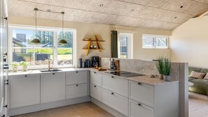 A modern kitchen with a large island, built-in cabinets, and a view of the outdoors. - "Indra" - 800m from the sea by Interhome (Løkken)