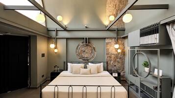 A modern bedroom with a large bed, a stone accent wall, and a skylight.