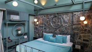 Ein modernes Schlafzimmer mit einer Steinwand, einem Bett mit blauer Bettwäsche und runden Wandleuchten.
