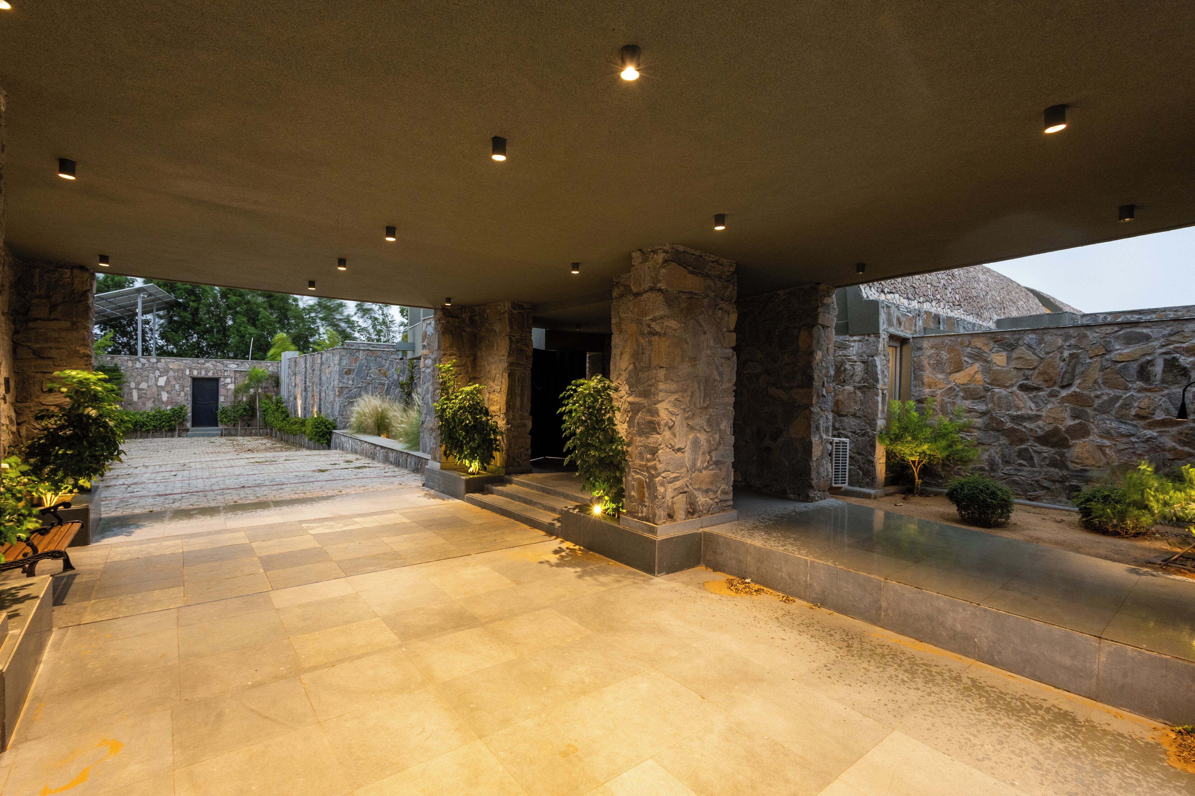 A covered outdoor area with stone walls, a paved floor, and potted plants.