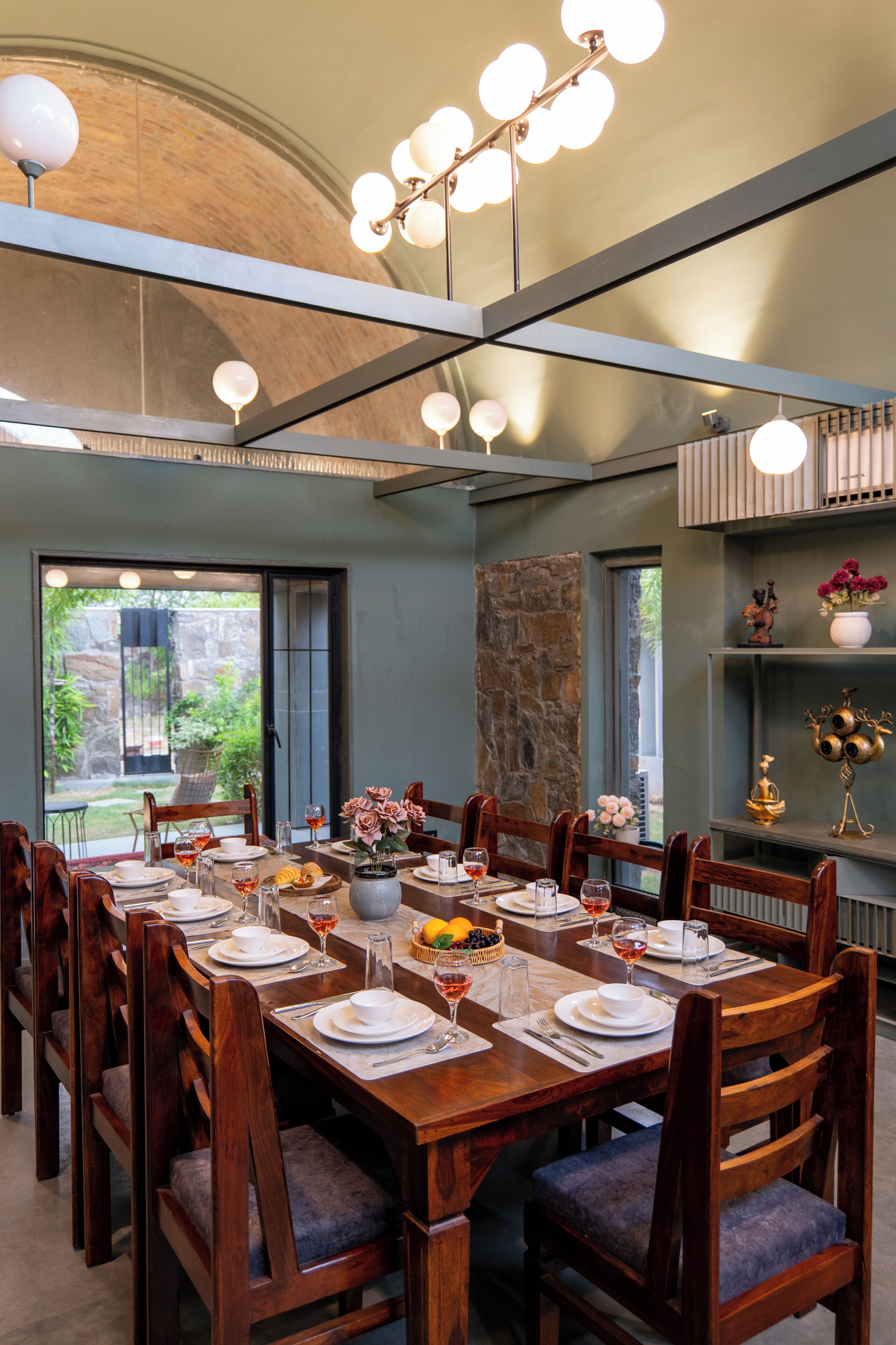A dining area with a long wooden table set for a meal, surrounded by chairs.
