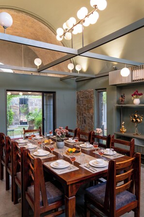 A dining area with a long wooden table set for a meal, surrounded by chairs.