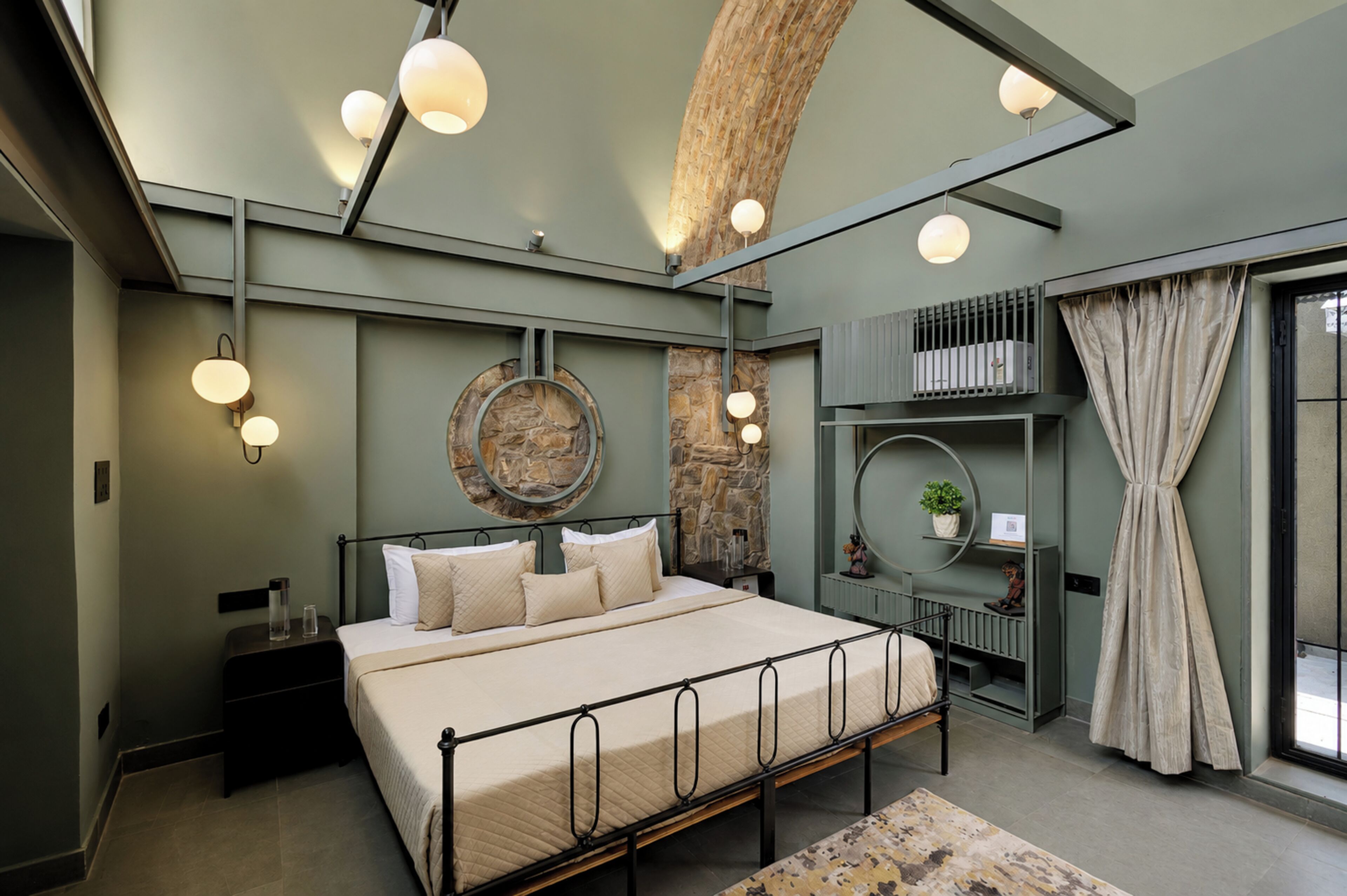 Un dormitorio moderno con cama, mesitas de noche, una pared de acento de piedra y un tragaluz.