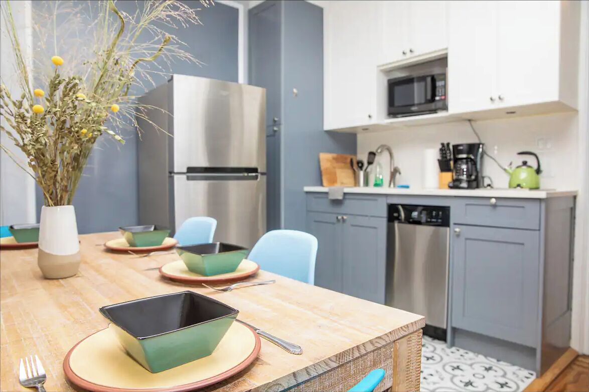 Een moderne keuken met witte kastjes, een roestvrijstalen koelkast, een magnetron en een koffiezetapparaat.