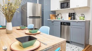 A modern kitchen with white cabinets, a stainless steel refrigerator, a microwave, and a coffee maker. - Modern 4-Bedroom Stay in the Heart of Lenox Hill! (New York)