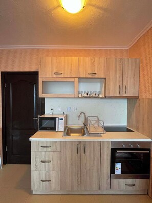 Una cucina compatta con mobili in legno, un forno a microonde, un lavello e una lavastoviglie.