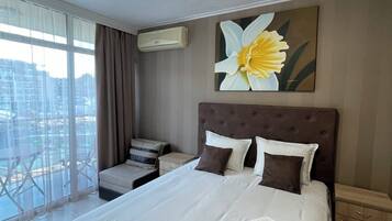 Een hotelkamer met een groot bed, uitzicht op de stad, een plafondlamp en een bloemschilderij.