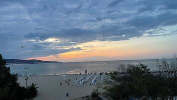 Een strand met parasols en ligbedden, een heldere lucht en een verre kustlijn.