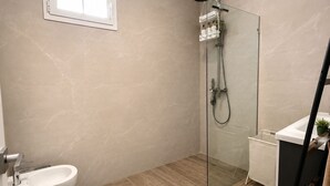 A modern bathroom with a toilet, bidet, shower, and a small window. - Laguna Beach 405- 300m from Dominicus Public Beach (Dominicus)
