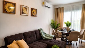 A modern living room with a dark brown sofa, a round wooden coffee table with a candle, and a dining area with a table and chairs. - Laguna Beach 405- 300m from Dominicus Public Beach (Dominicus)
