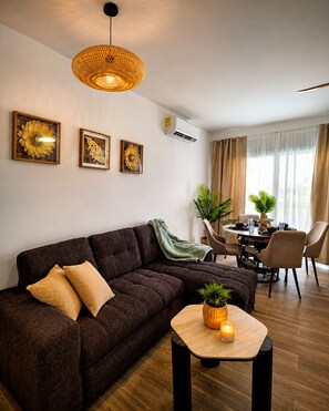 A modern living room with a dark brown sofa, a round wooden coffee table with a candle, and a dining area with a table and chairs. - Laguna Beach 405- 300m from Dominicus Public Beach (Dominicus)