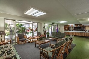 Eine großzügige Lobby mit Korbmöbeln, einem Empfangsschalter und großen Fenstern mit Jalousien.
