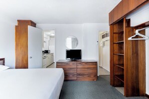 Ein Hotelzimmer mit einem Bett, einer Holzkommode, einem Fernseher, einem Spiegel und einem Kleiderschrank.