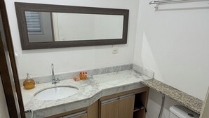 Een badkamer met een witte wastafel, houten kastjes, een spiegel en een toilet.