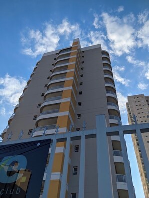 A tall building with multiple balconies, a clear sky, and a partial view of another building. - Flat - unique and comfortable (Jundiaí)