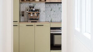 A kitchen with a built-in coffee machine, a spice rack, and a microwave. - Stunning Designer Apartment in the Heart of Paris (11th Arrondissement) (Paris)