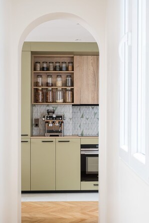 A kitchen with a built-in coffee machine, a spice rack, and a microwave. - Stunning Designer Apartment in the Heart of Paris (11th Arrondissement) (Paris)