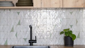 A kitchen with a sink, wooden cabinets, and a tiled backsplash. - Stunning Designer Apartment in the Heart of Paris (11th Arrondissement) (Paris)