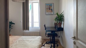 A bedroom with a bed, a desk, a chair, a hanging lamp, a window, and a potted plant. - Stunning Designer Apartment in the Heart of Paris (11th Arrondissement) (Paris)