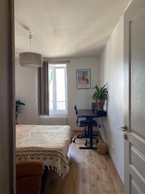 A bedroom with a bed, a desk, a chair, a hanging lamp, a window, and a potted plant. - Stunning Designer Apartment in the Heart of Paris (11th Arrondissement) (Paris)