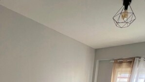 Une chambre à coucher comprenant un lit, une table de chevet, un banc et un luminaire suspendu.