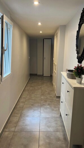 A hallway with a tiled floor, a door at the end, and a vanity with a mirror and a potted plant. - Gandia, between the beach and the harbor: 100 m² of comfort (Gandia)