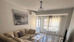 Un salon avec un canapé d’angle beige, une table basse blanche et un téléviseur à écran plat posé sur un meuble.