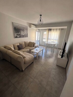 A living room with a beige sectional sofa, a white coffee table, and a flat-screen TV on a stand. - Gandia, between the beach and the harbor: 100 m² of comfort (Gandia)