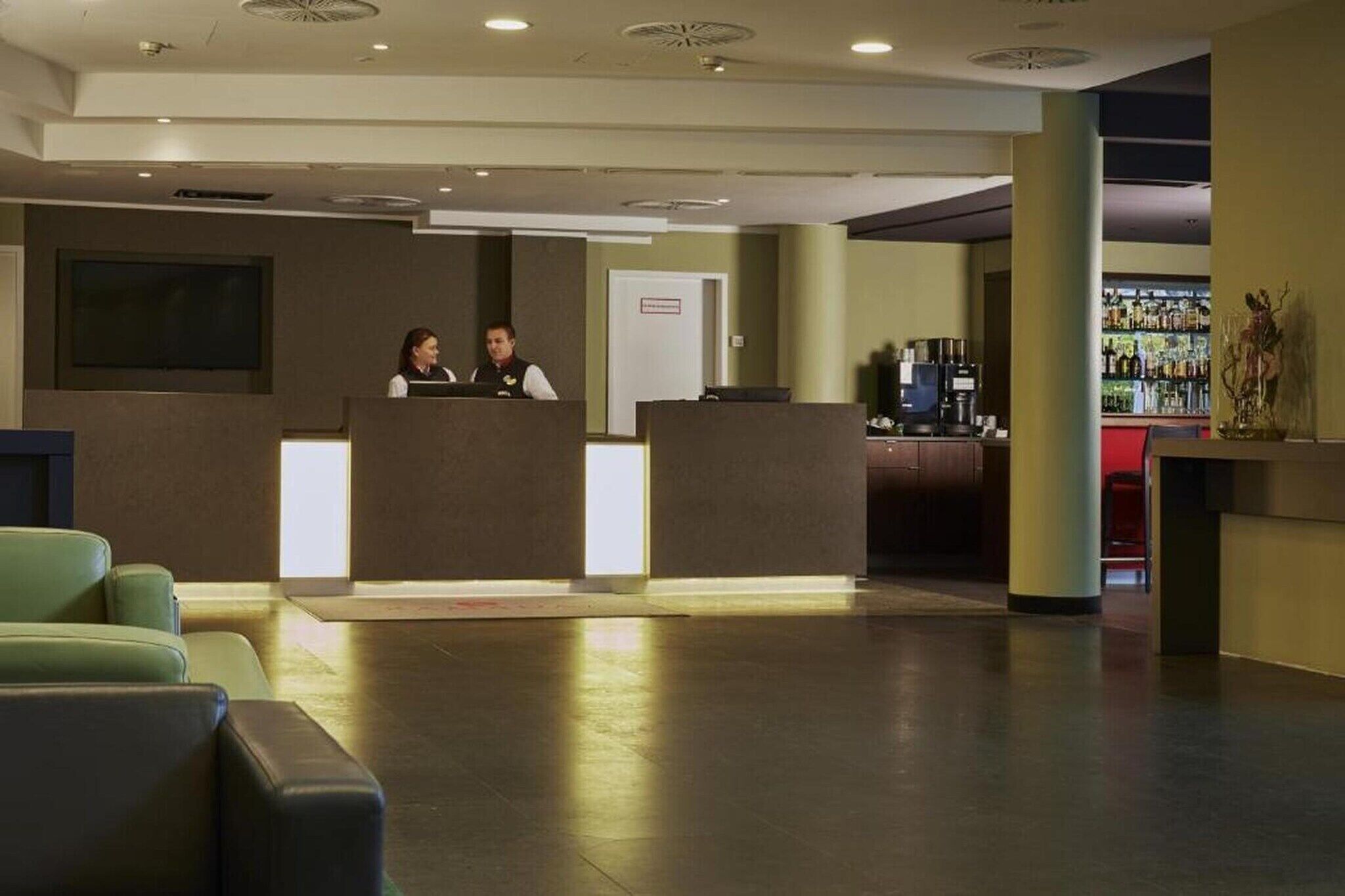 Et hotellets receptionsområde med reception, bar og siddepladser.