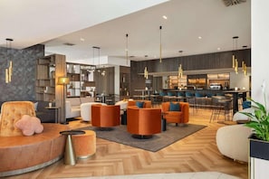 Een moderne hotellobby met zithoeken, een bar en een receptiebalie.