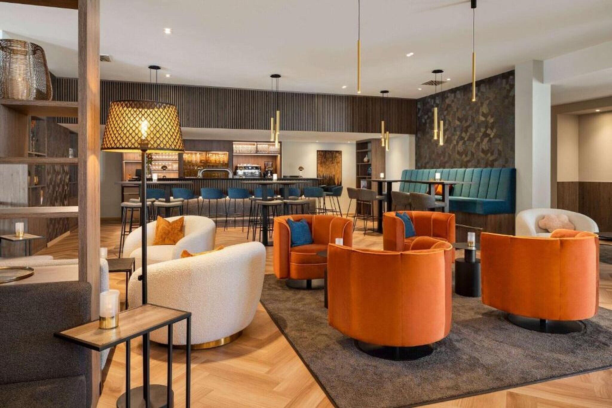 Un hall d’hôtel moderne, doté d’espaces aménagés avec des sièges, d’un bar et d’un comptoir de réception.
