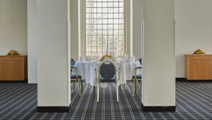 A dining area with a table set for four, a window with a grid pattern, and a carpeted floor. - Sunday Hotel Köln Hürth Disability Access (Hürth)