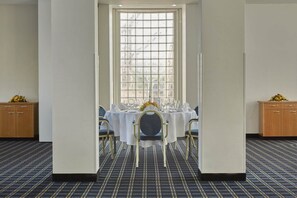 Ein Essbereich mit einem Tisch für vier Personen, einem fenster mit Gittermuster und einem Teppichboden.