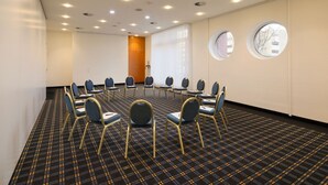 A conference room with a circular table, blue chairs, and a patterned carpet. - Sunday Hotel Köln Hürth Disability Access (Hürth)