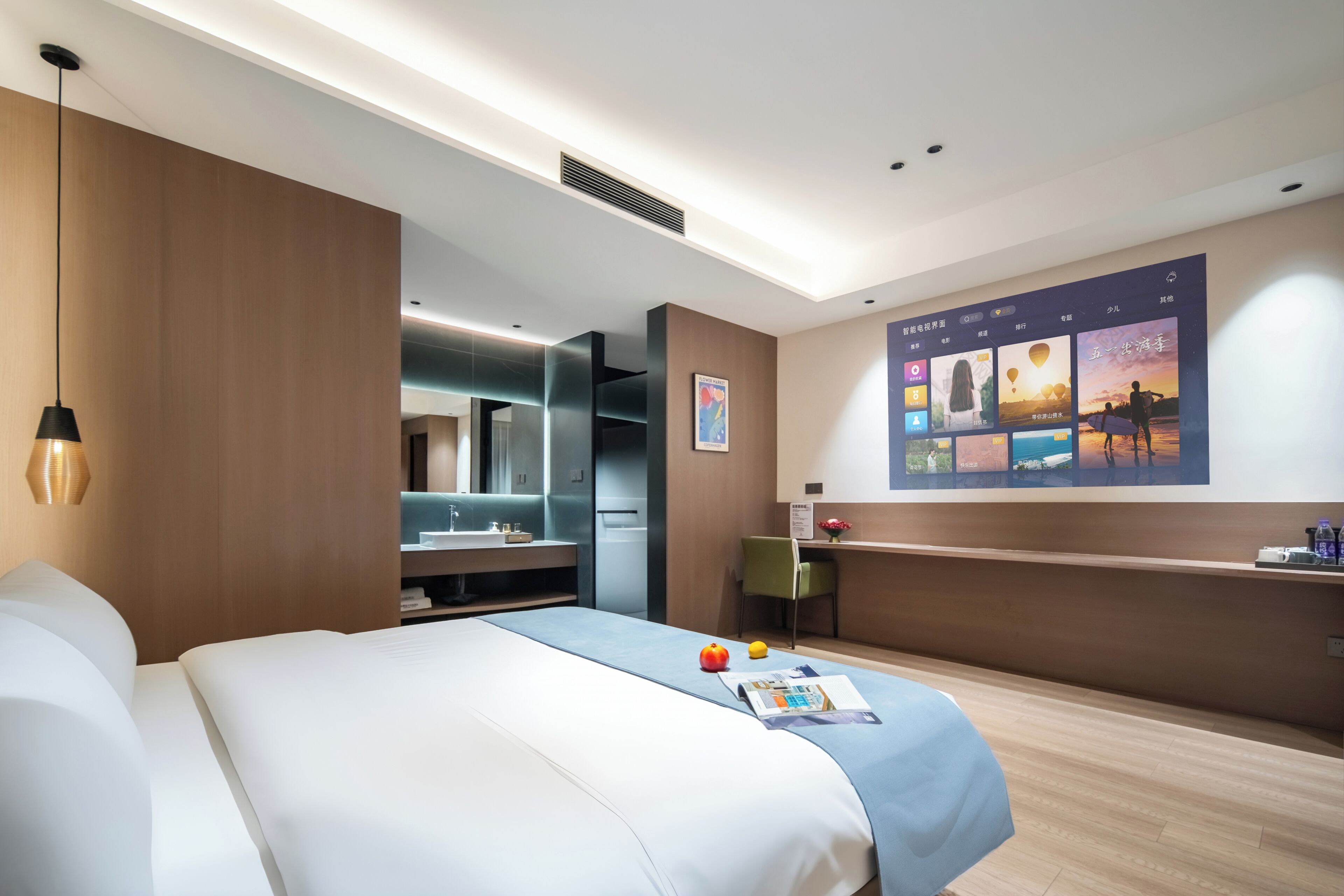 Una habitación de hotel moderna con una cama, un escritorio y una gran pantalla digital en la pared.