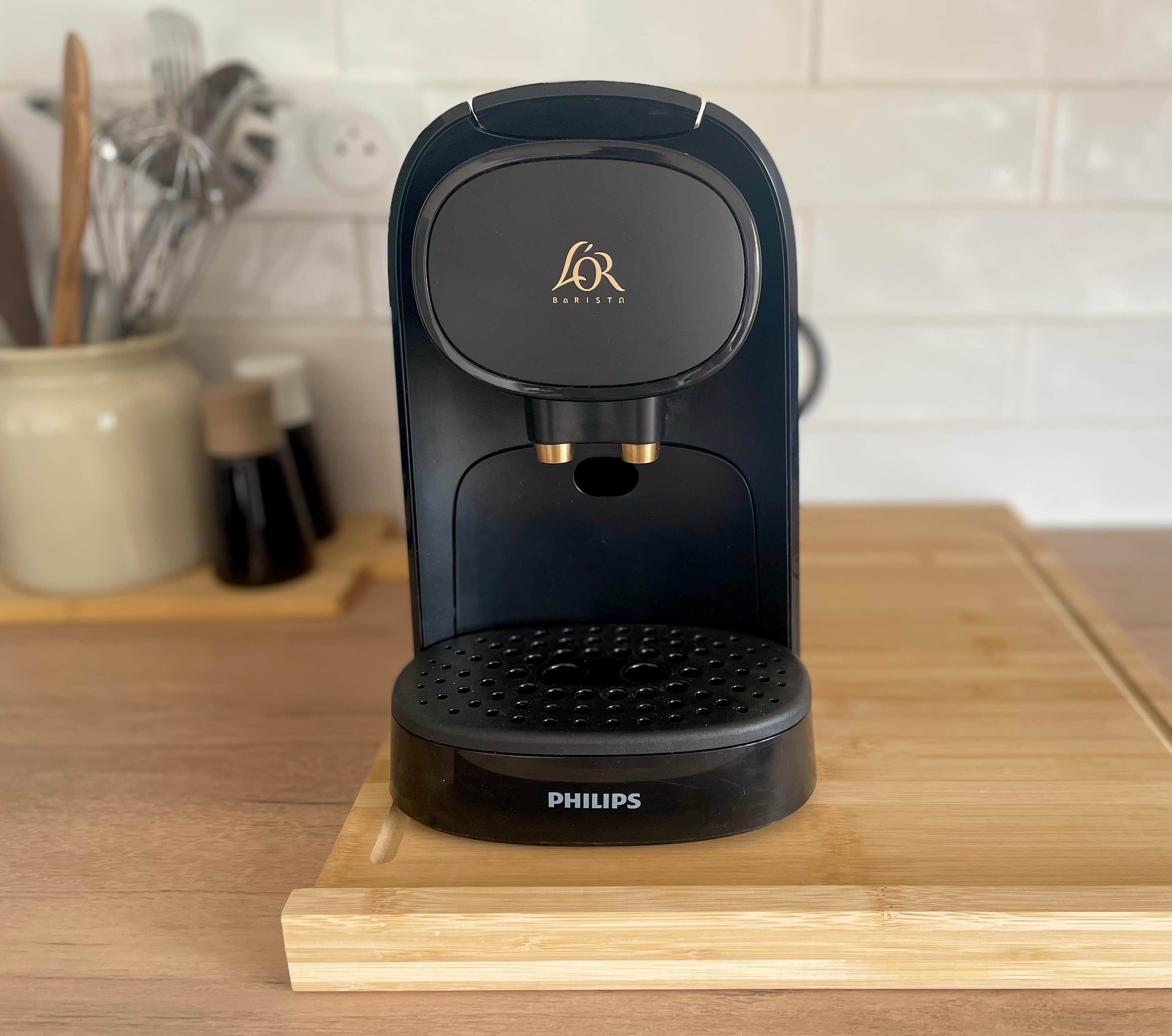 Een zwarte Philips koffiezetapparaat met een drupplade met gaatjes op een houten oppervlak.