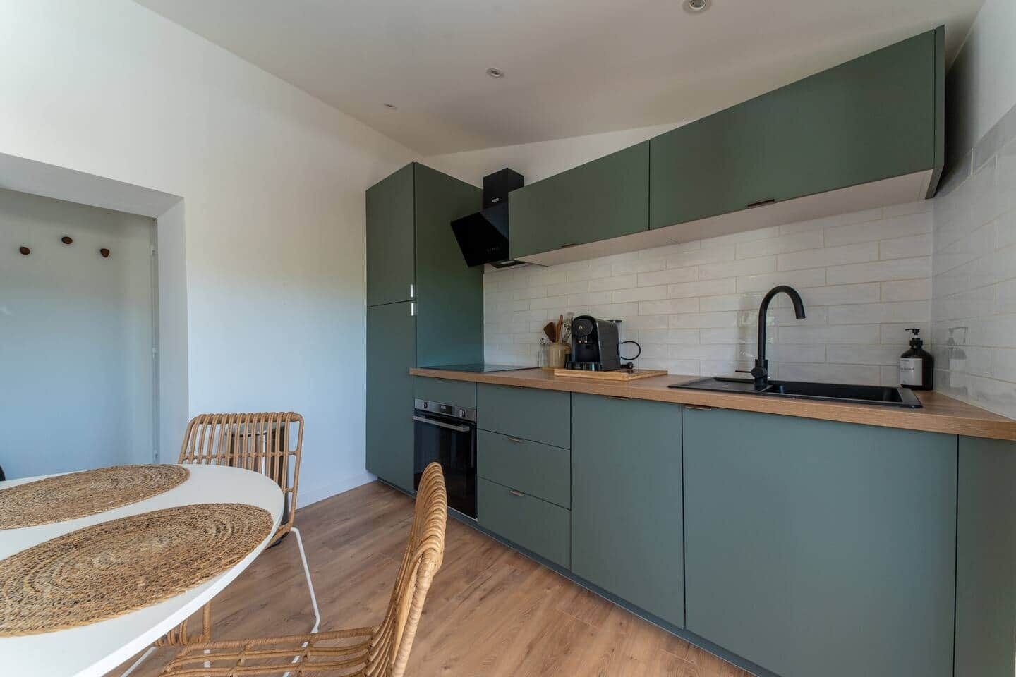 A compact kitchen with a built-in oven, a coffee machine, and a sink.