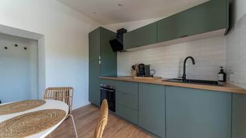 A compact kitchen with a built-in oven, a coffee machine, and a sink.