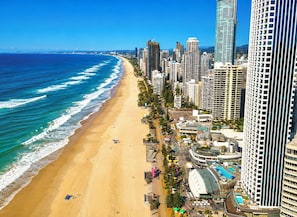 A coastal cityscape with a beach, high-rise buildings, and a large hotel complex with a pool. - Robin's Oceanview Penthouse | 1 Min to Beach (Surfers Paradise)